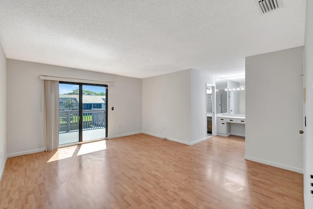 unfurnished room featuring visible vents, baseboards, a textured ceiling, and light wood finished floors