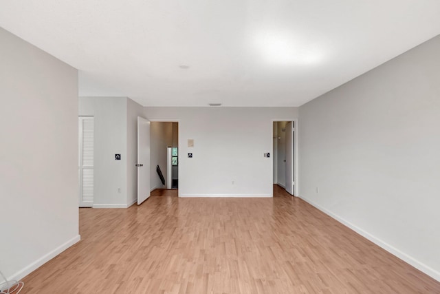 unfurnished room with light wood-type flooring and baseboards