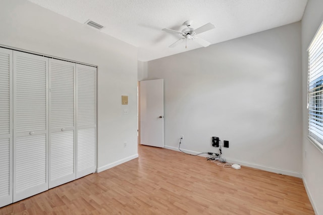 unfurnished bedroom with visible vents, baseboards, light wood-style floors, a closet, and a textured ceiling