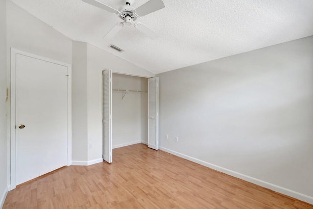 unfurnished bedroom featuring visible vents, light wood-style flooring, a textured ceiling, a closet, and vaulted ceiling