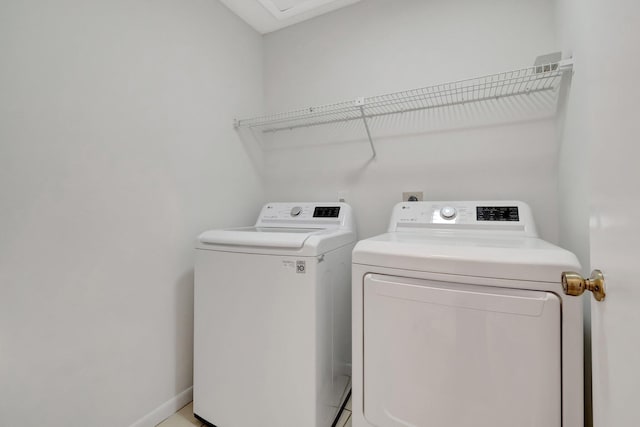 washroom featuring laundry area, baseboards, and washing machine and clothes dryer