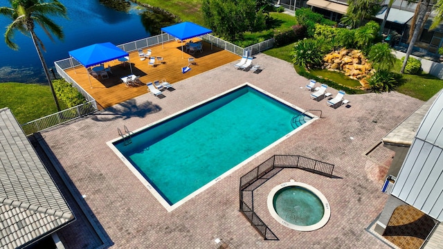 community pool featuring a water view, a community hot tub, a patio, fence, and a gazebo