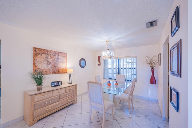 dining area with light tile patterned floors, visible vents, a textured ceiling, and an inviting chandelier