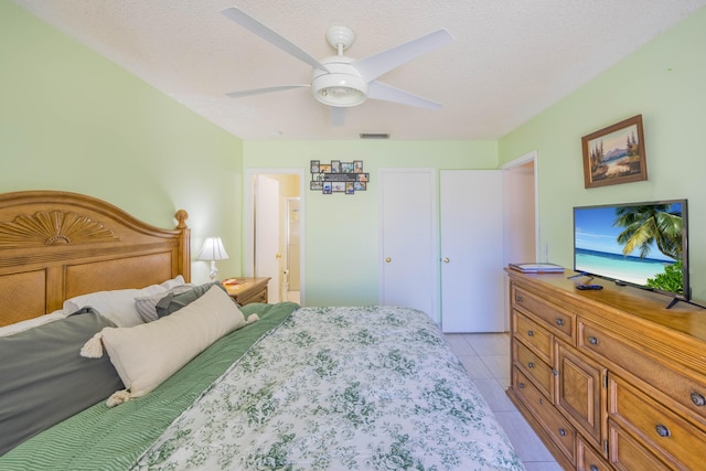 bedroom featuring light tile patterned flooring, visible vents, a textured ceiling, and a ceiling fan