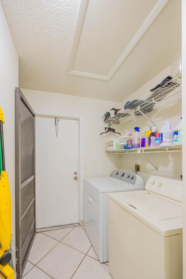 laundry room with washer and dryer, a textured ceiling, laundry area, and light tile patterned floors