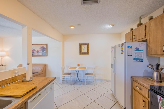 kitchen featuring visible vents, baseboards, light tile patterned floors, white dishwasher, and a textured ceiling