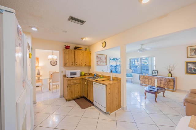 kitchen featuring white appliances, light tile patterned floors, visible vents, and a sink