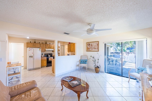 living area with visible vents, a ceiling fan, a textured ceiling, light tile patterned floors, and baseboards