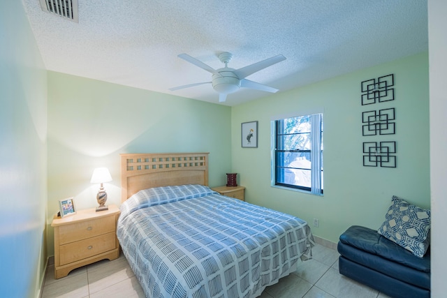 bedroom with visible vents, a textured ceiling, light tile patterned flooring, and a ceiling fan