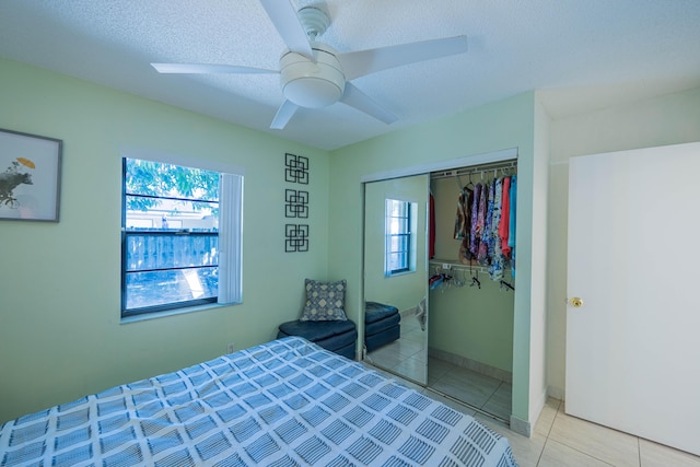 bedroom featuring light tile patterned flooring, a ceiling fan, a closet, and a textured ceiling