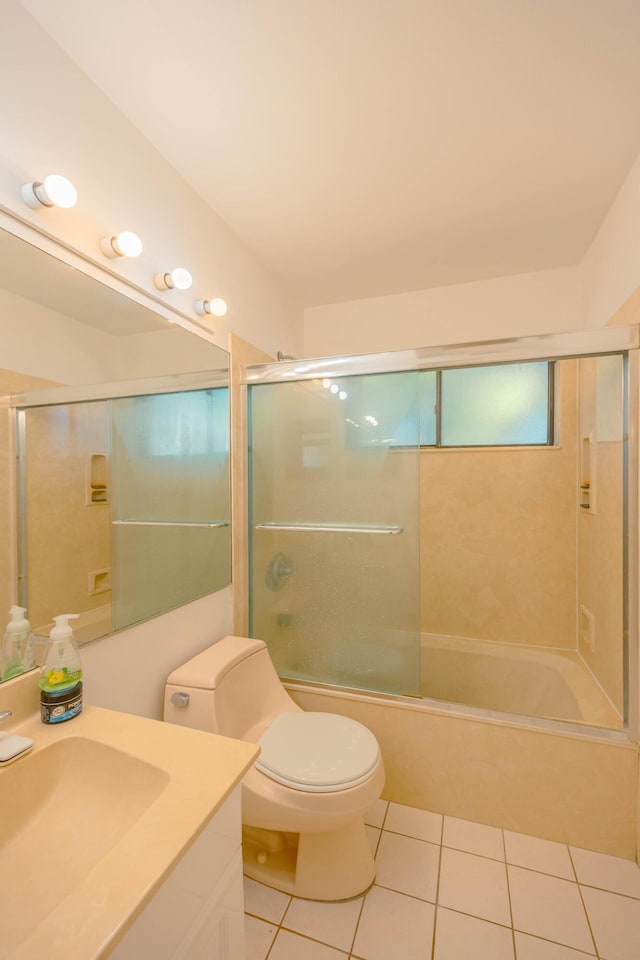 bathroom featuring tile patterned floors, enclosed tub / shower combo, toilet, and vanity