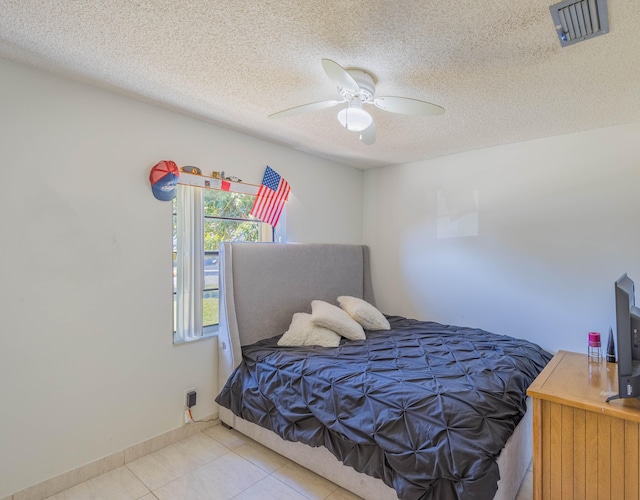 bedroom with visible vents, baseboards, ceiling fan, light tile patterned flooring, and a textured ceiling