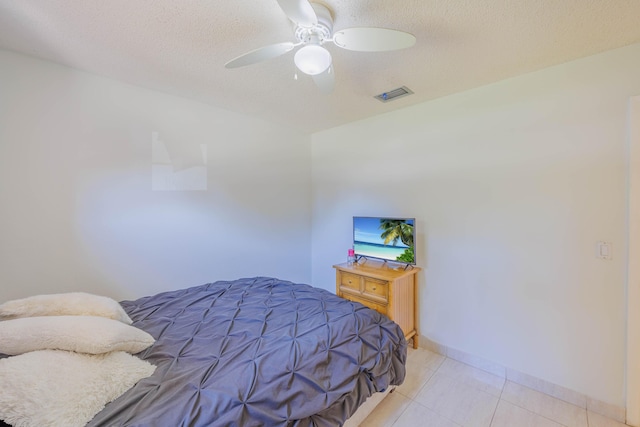 bedroom featuring light tile patterned floors, baseboards, visible vents, and a textured ceiling