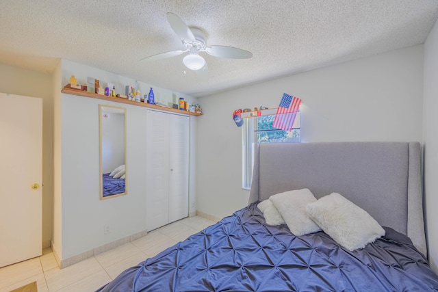 tiled bedroom featuring baseboards, a ceiling fan, a closet, and a textured ceiling