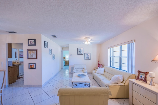 living room with ceiling fan, light tile patterned floors, visible vents, and a textured ceiling