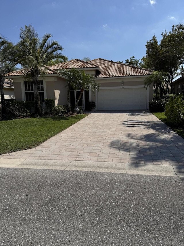 view of front of house with stucco siding, decorative driveway, an attached garage, and a tile roof