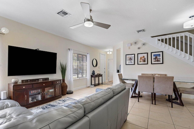 living room with a ceiling fan, light tile patterned floors, stairs, and visible vents