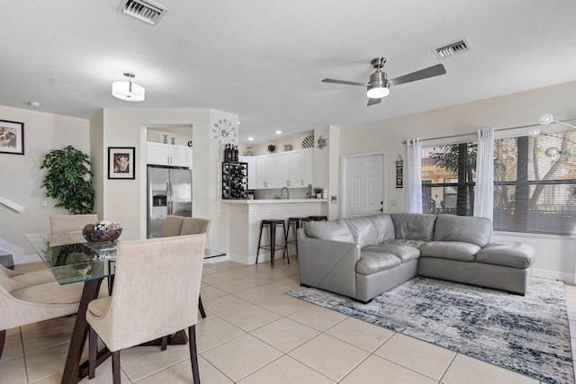 living room with a ceiling fan, visible vents, and light tile patterned floors