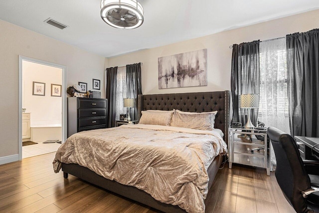 bedroom featuring visible vents, wood finished floors, and ensuite bathroom