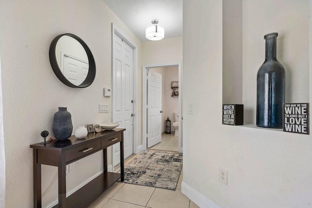hallway featuring light tile patterned floors and baseboards