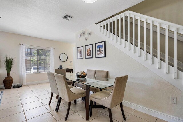 dining space featuring stairs, baseboards, a textured ceiling, tile patterned floors, and visible vents