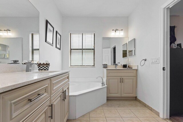 full bath featuring a garden tub, a sink, tile patterned floors, and two vanities