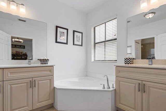 bathroom with a sink, two vanities, a garden tub, and visible vents