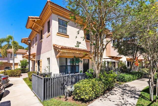 exterior space with a fenced front yard, a tiled roof, and stucco siding