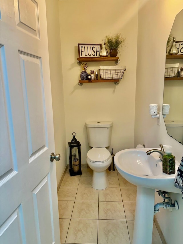 half bathroom with tile patterned floors, toilet, and baseboards