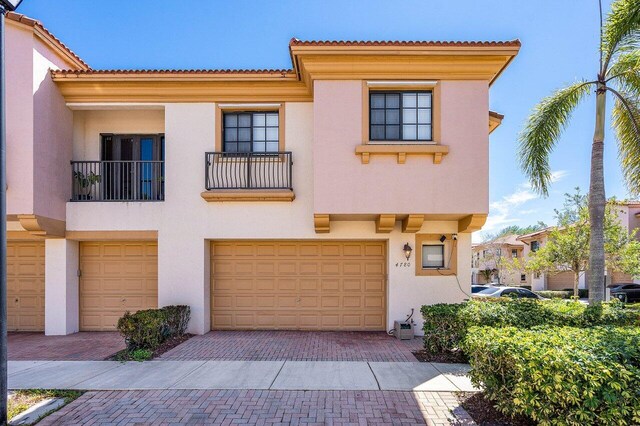 view of front facade featuring decorative driveway, a tiled roof, stucco siding, and an attached garage