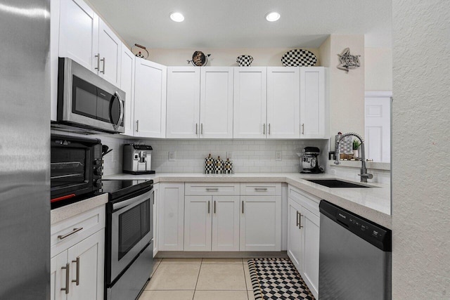 kitchen featuring light countertops, a sink, tasteful backsplash, and appliances with stainless steel finishes