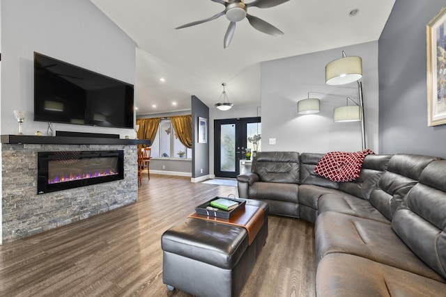 living room with ceiling fan, baseboards, a stone fireplace, french doors, and wood finished floors