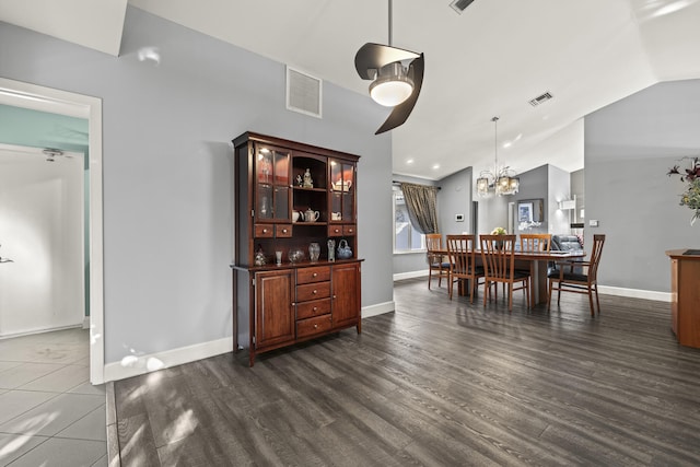 dining room featuring visible vents, dark wood-style flooring, baseboards, and vaulted ceiling