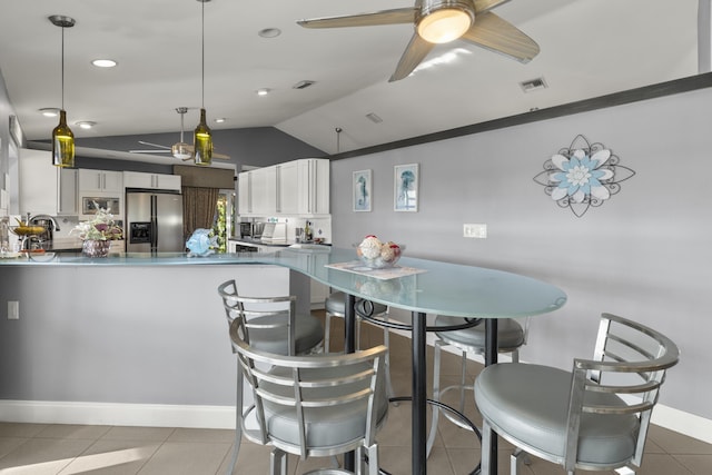 kitchen featuring light tile patterned floors, visible vents, a peninsula, stainless steel appliances, and white cabinets