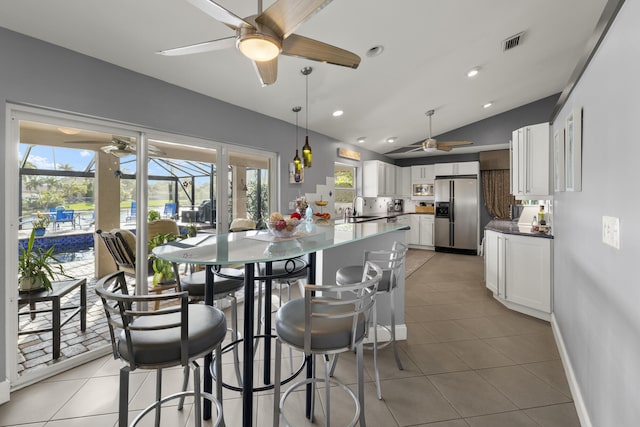 dining space with vaulted ceiling, plenty of natural light, visible vents, and light tile patterned floors