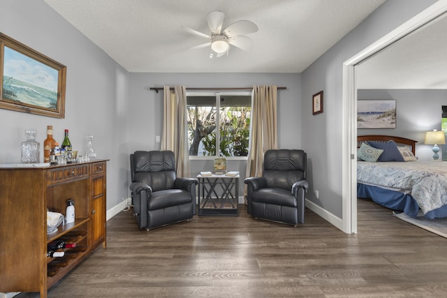 sitting room featuring ceiling fan, baseboards, and dark wood-style floors