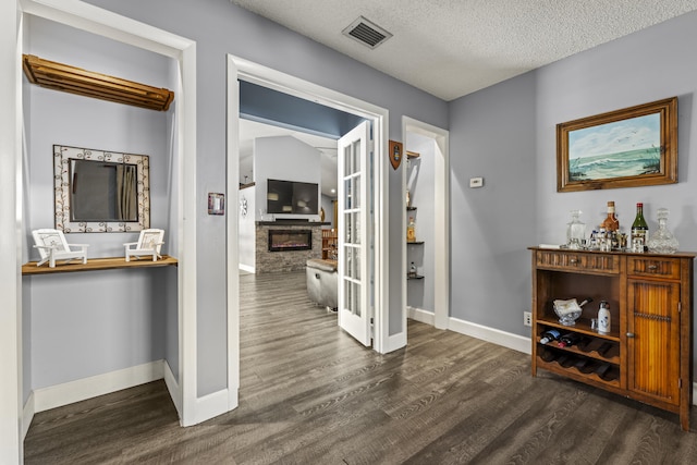 hall featuring visible vents, a textured ceiling, dark wood-type flooring, and baseboards