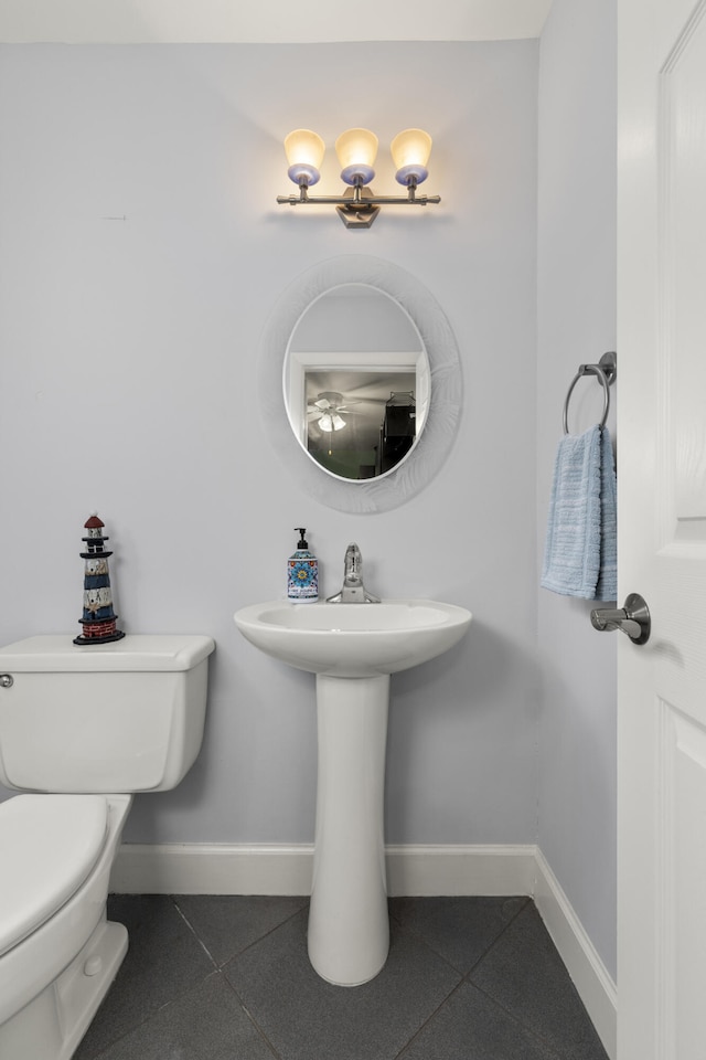 bathroom featuring a sink, baseboards, toilet, and tile patterned flooring