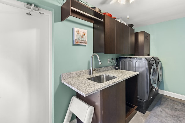 clothes washing area with a sink, baseboards, cabinet space, and washing machine and dryer