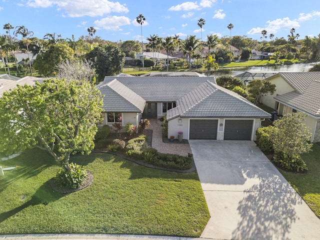 ranch-style home featuring a tile roof, an attached garage, concrete driveway, and a front lawn