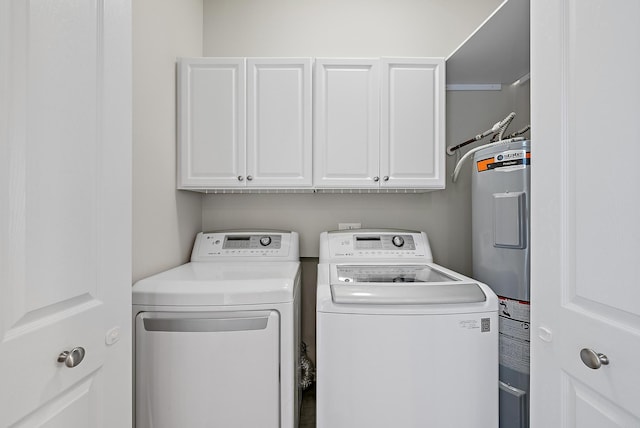 washroom with cabinet space, water heater, and washer and clothes dryer