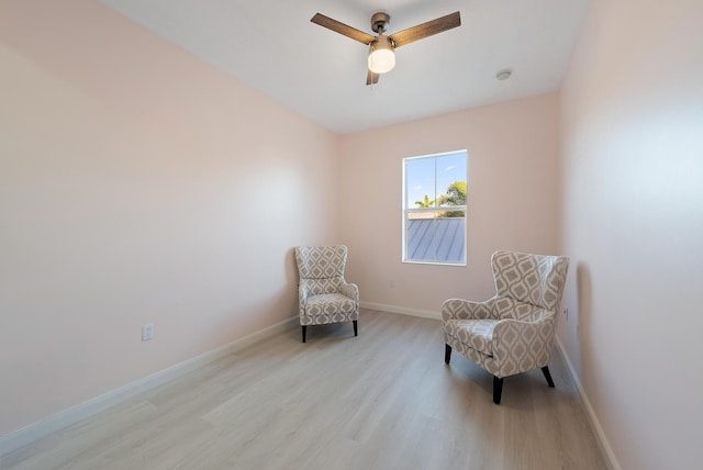 living area featuring ceiling fan, baseboards, and wood finished floors