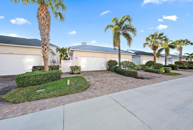 single story home featuring a gate, fence, a garage, decorative driveway, and metal roof