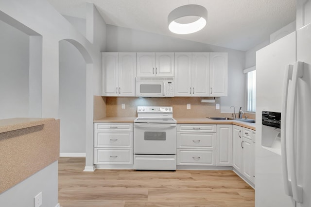 15443 Floral Club Rd, Delray Beach, FL 33484 - kitchen with light countertops, lofted ceiling, white appliances, white cabinetry, and a sink