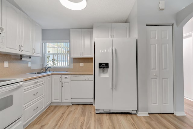 15443 Floral Club Rd, Delray Beach, FL 33484 - kitchen with white appliances, white cabinets, light wood finished floors, and a sink