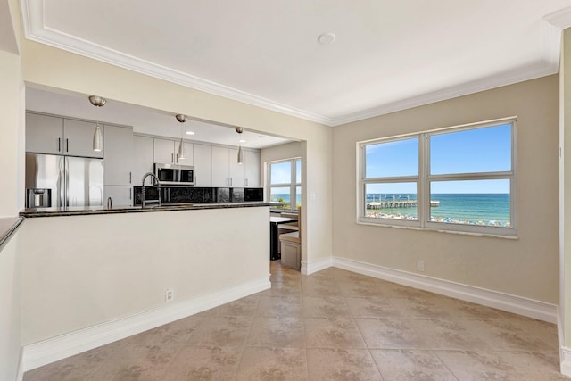 kitchen featuring baseboards, stainless steel appliances, a water view, crown molding, and decorative light fixtures