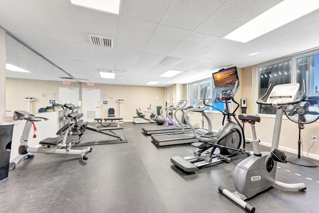 exercise room with baseboards, visible vents, and a drop ceiling