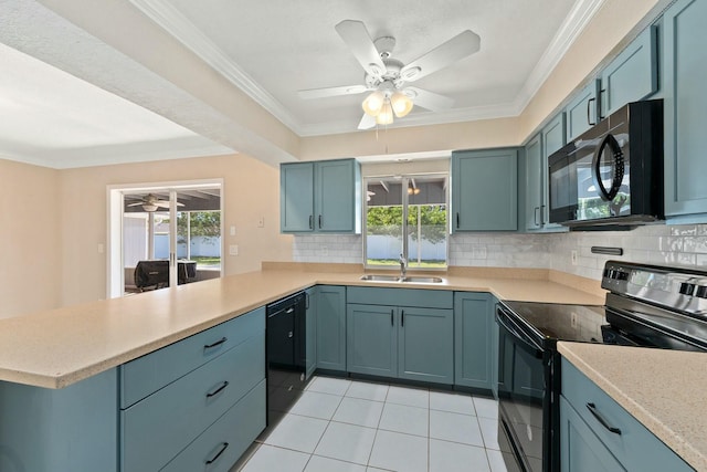 kitchen featuring light countertops, decorative backsplash, a peninsula, black appliances, and a sink