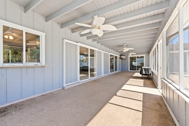 unfurnished sunroom featuring beamed ceiling and a ceiling fan