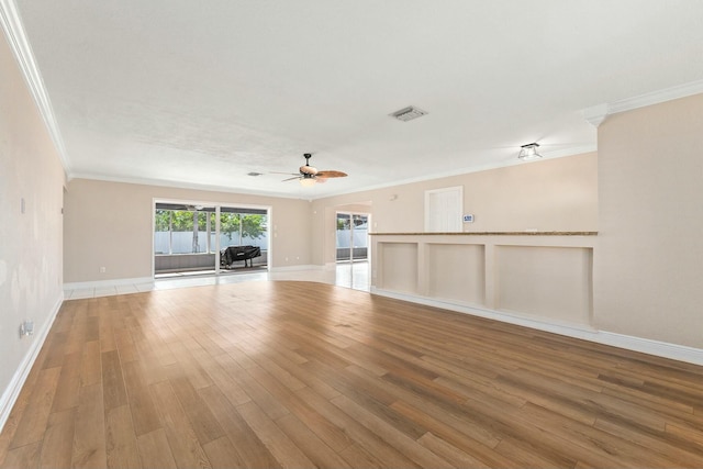 empty room featuring ceiling fan, visible vents, wood finished floors, and crown molding